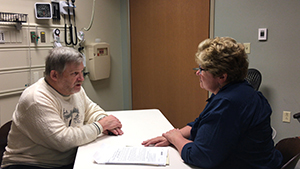 Simulated patient and physician seated at table