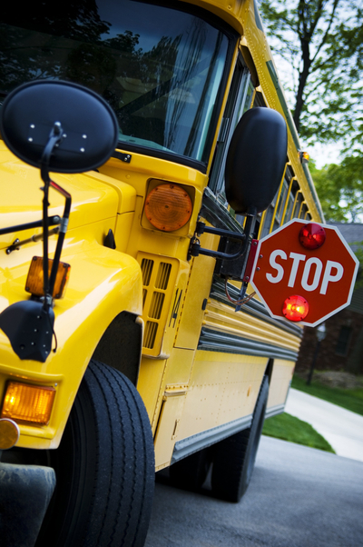 Front-side view of a yellow school bus with its stop sign arm extended.