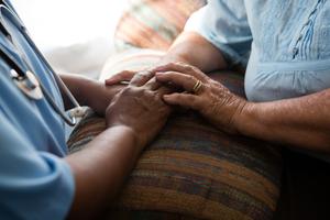 care provider and a senior adult holding hands supportively