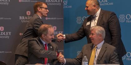 Leaders from OSF HealthCare and Bradley University shake hands at press conference