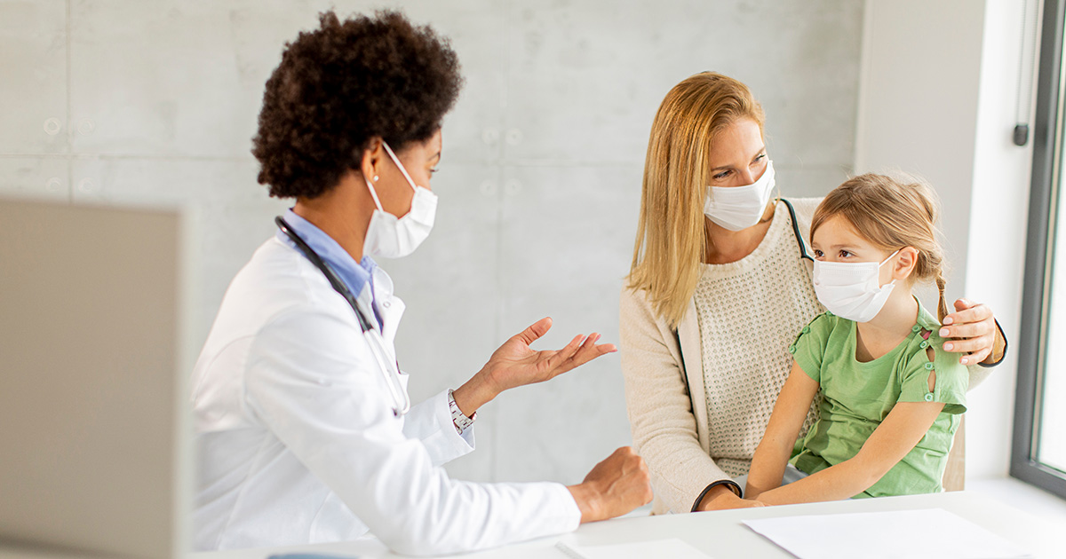 Doctor seeing mother and daughter wearing facemasks
