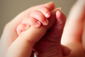 Woman holding infant's hand