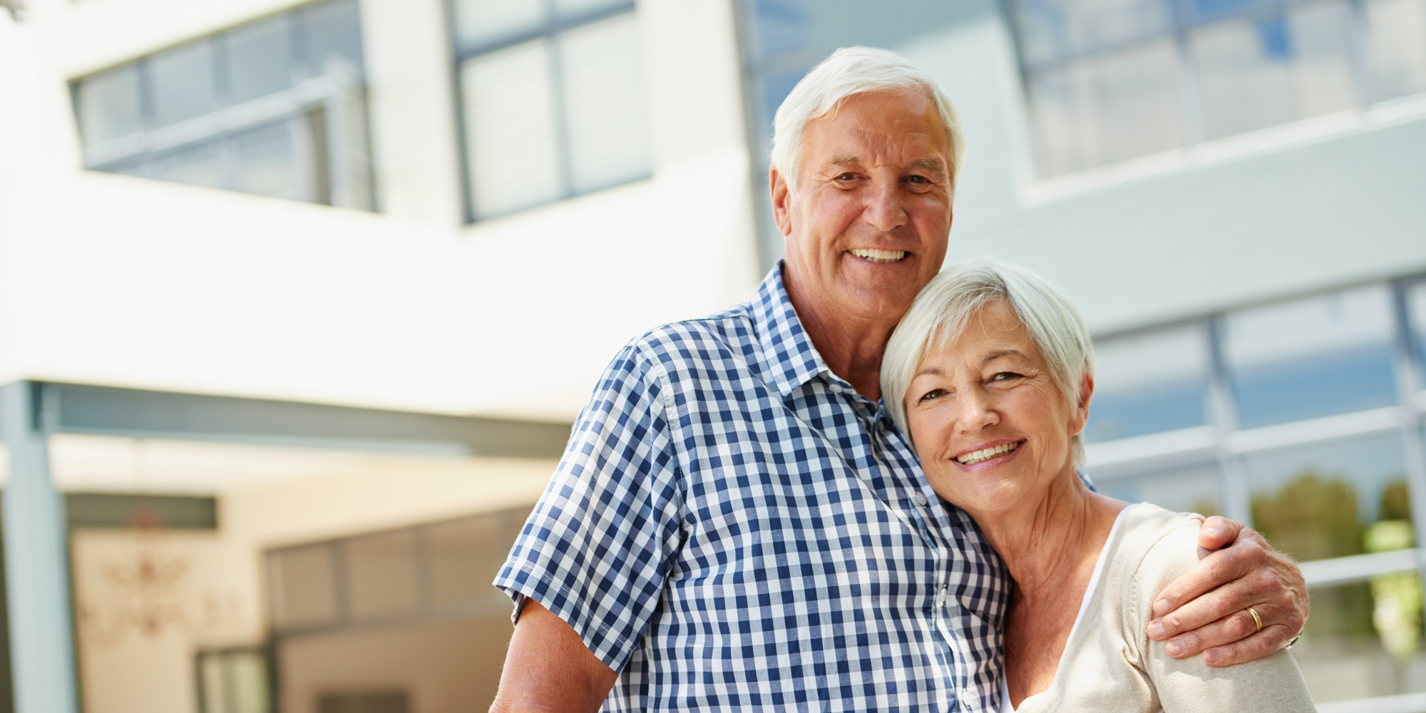 Senior couple hugging and smiling outside of a clinic