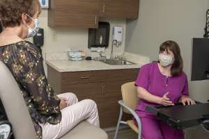 Physician speaks with patient in clinic exam room