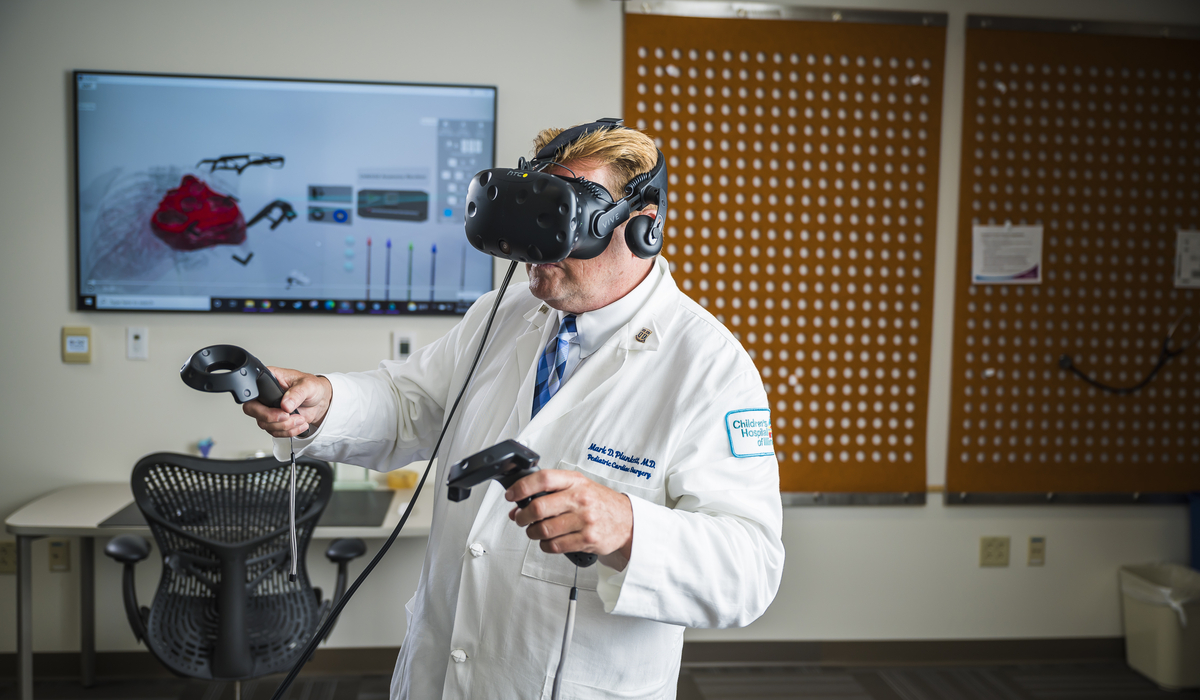 male in lab coat and VR headset holds VR controllers in each hand