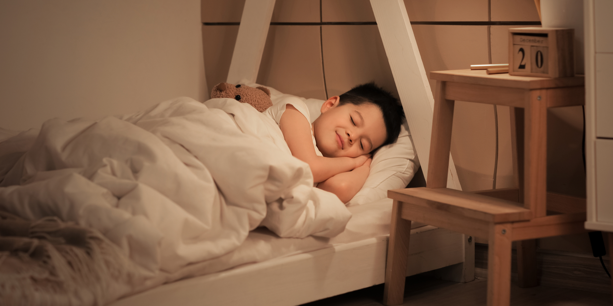 young boy sleeps with a smile in a bedroom
