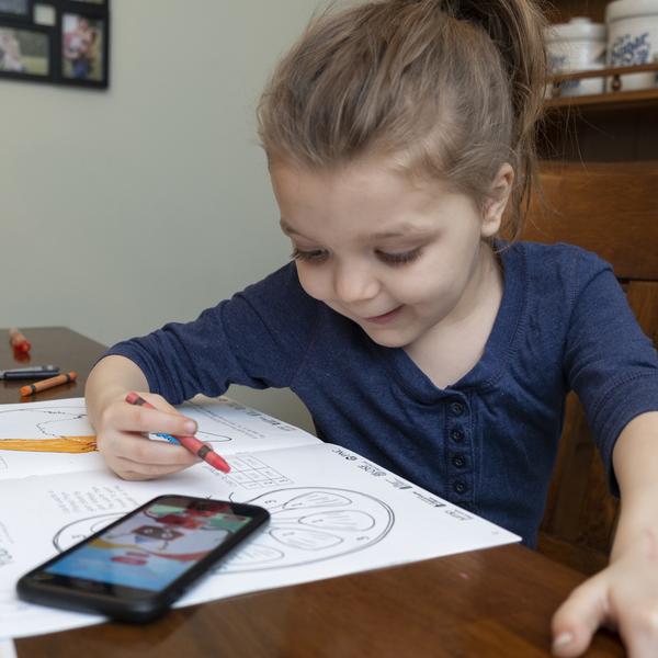 Young girl using About Me 3D Activity Book and mobile device