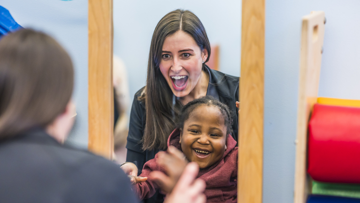 Physical therapist with child patient looking in mirror