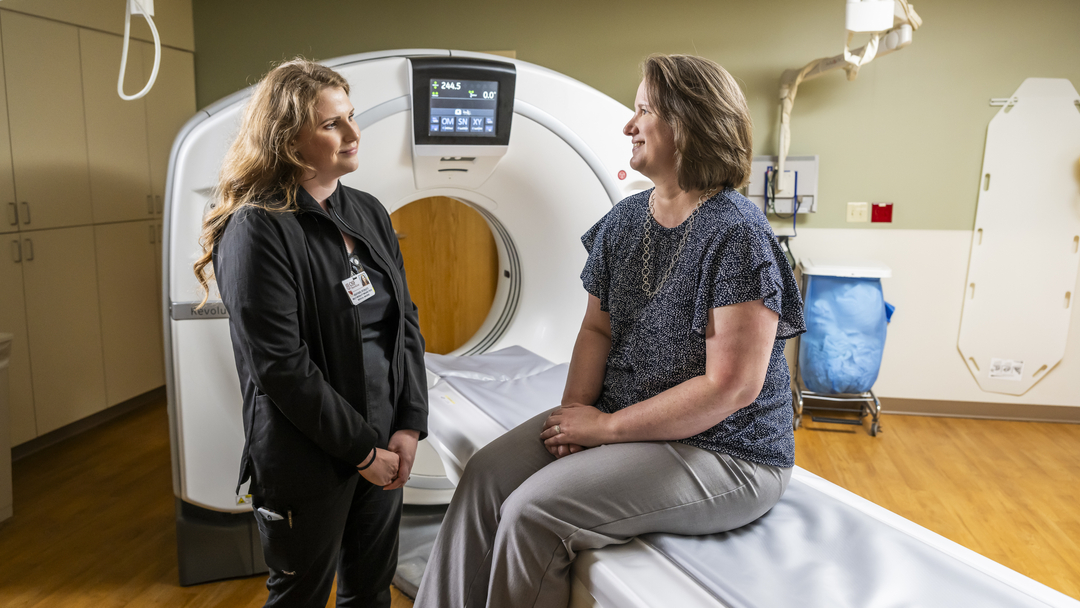 Doctor with female patient sitting on CT scanner