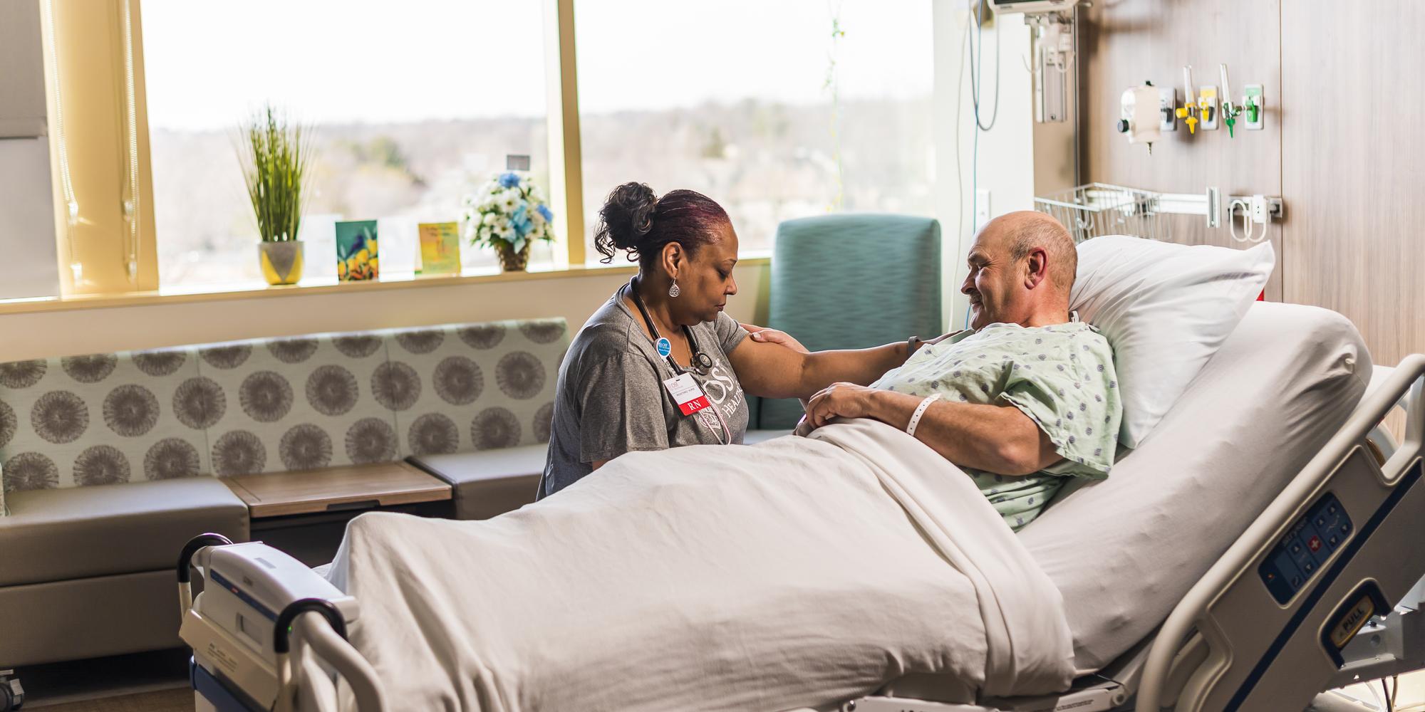 Nurse praying with patient at his bedside