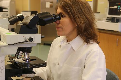 Lab tech looking through microscope| OSF Saint Clare Medical Center