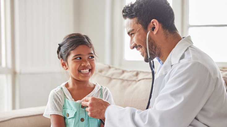 Doctor with stethoscope listening to girl's chest
