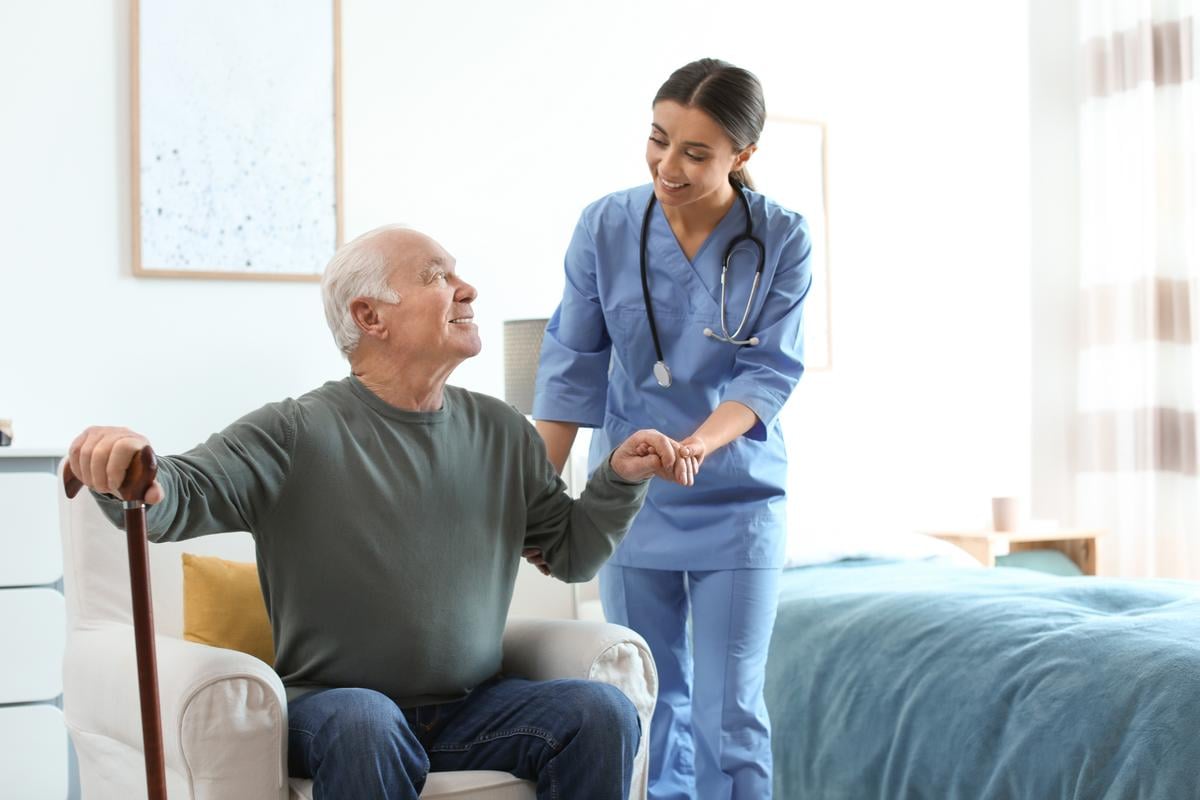 Nurse helping a man with a cane