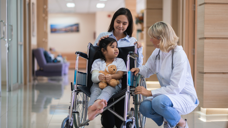 Child in wheelchair holding teddy bear