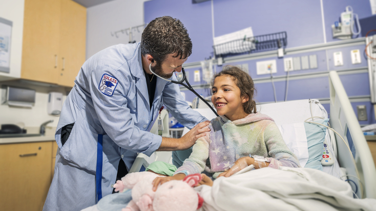 Physician listening to girl's heart