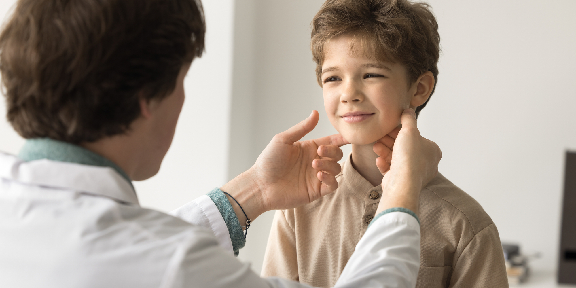 Young man otolaryngologist in white coat examine lymph touches nodes of little kid patient.