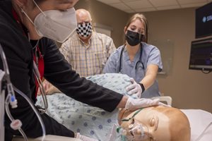 Nurse team working with manikin on hospital bed