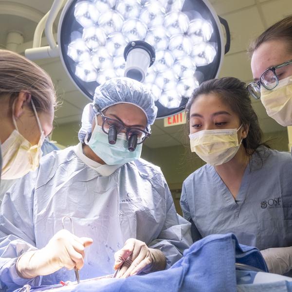 Group of students learn from physician in a mock operation.