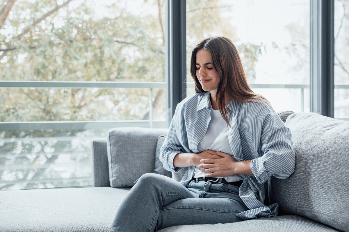 Young Woman Grimaces and Holds her Stomach