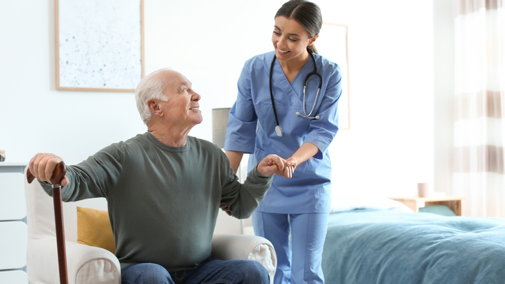 Nurse helping a man with a cane