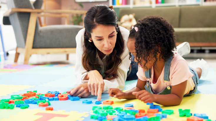 Adult female playing with child on the floor