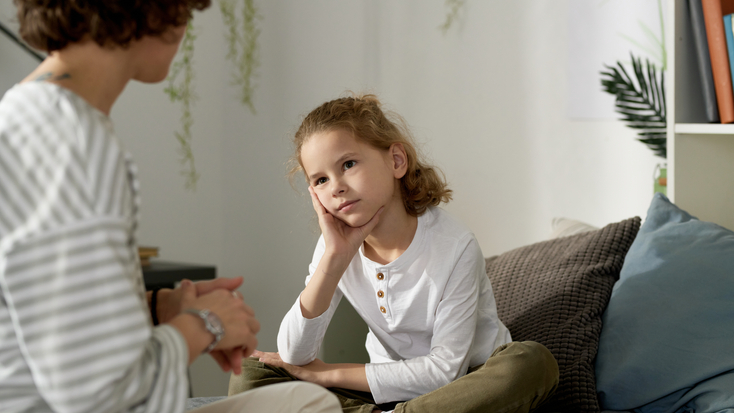 A supportive adult engaging in a serious, heart-to-heart discussion with a young child to provide emotional support.