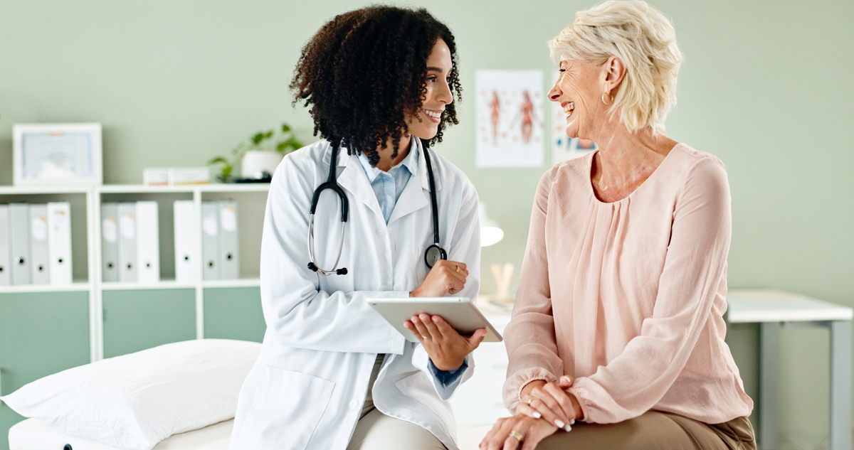 Young Provider Converses with a Laughing Senior Patient 