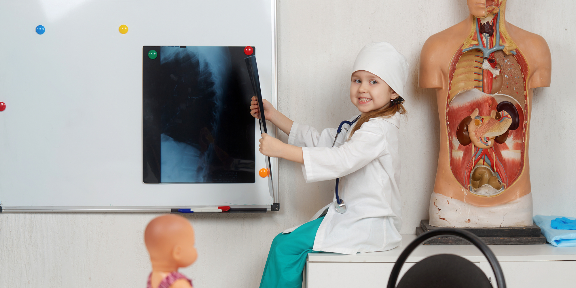 little girl doctor smiles holding x-ray