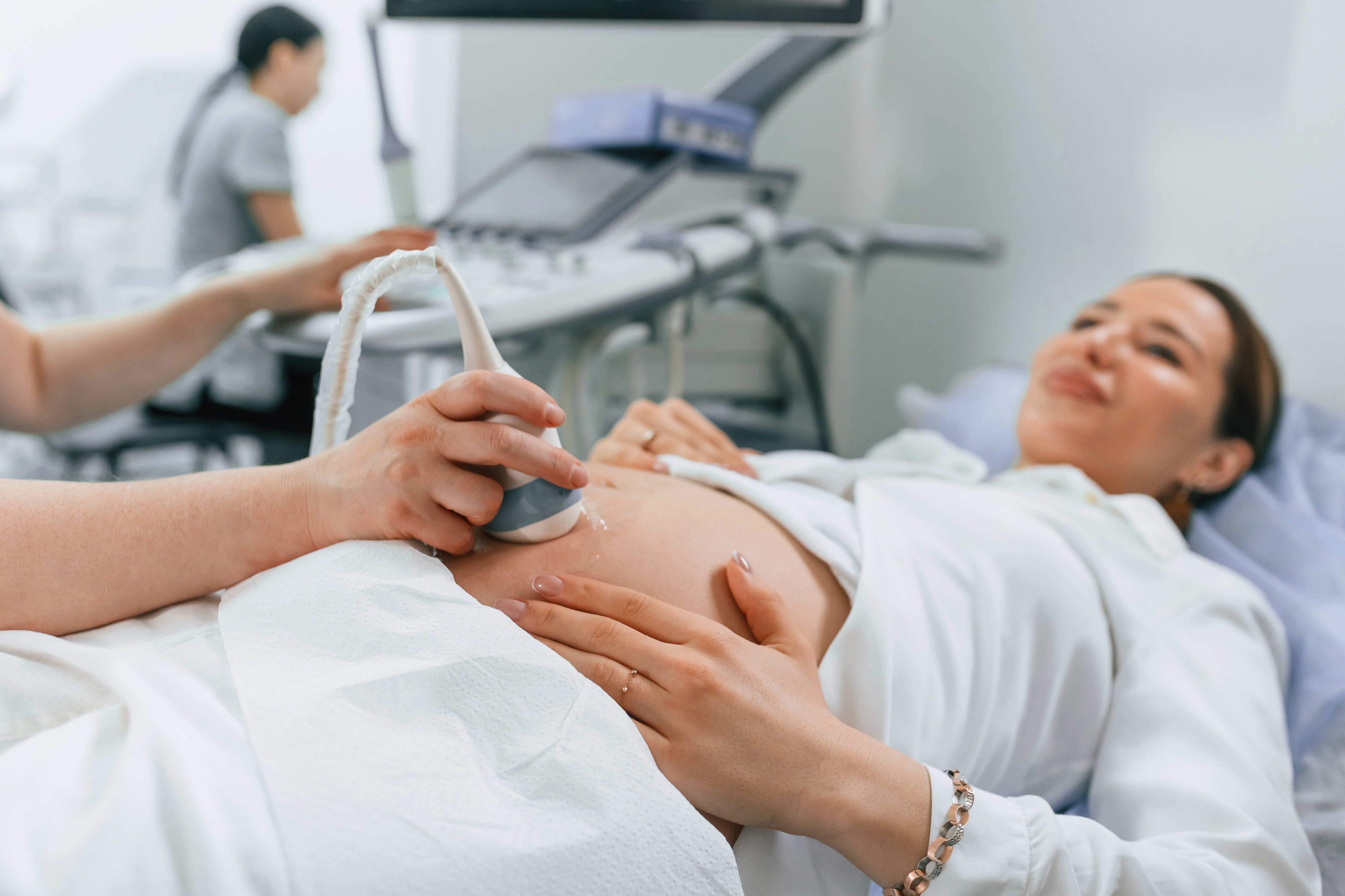 A medical professional performs an ultrasound on a pregnant patient in a clinic setting.