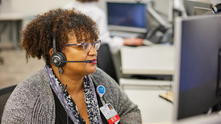 An OSF OnCall nurse triage representative wearing a telephone headset handles a patient call from a workstation.