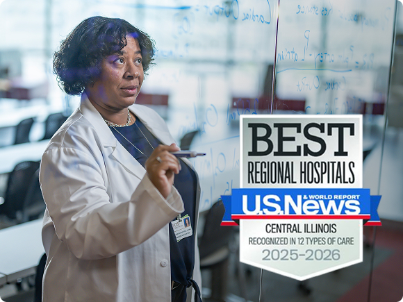Doctor writing on a glass wall and showing US News badge for Best Regional Hospitals