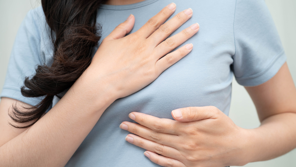 Woman pressing on her own breast for density