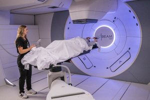 A healthcare professional preparing a patient on a treatment table for a radiation therapy session.