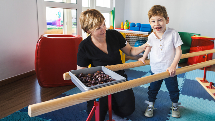 Physical therapist helping child learn to walk