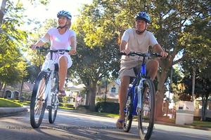 two male and female adults ride bicycles down a street