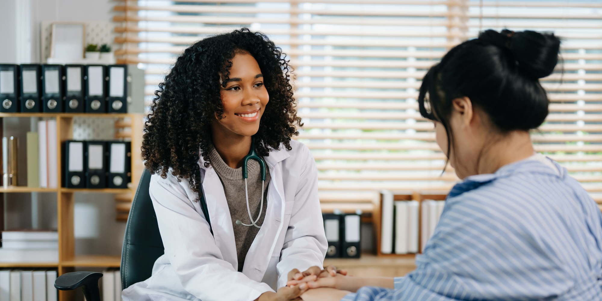 Female Provider Smiles and Holds Hands with Patient