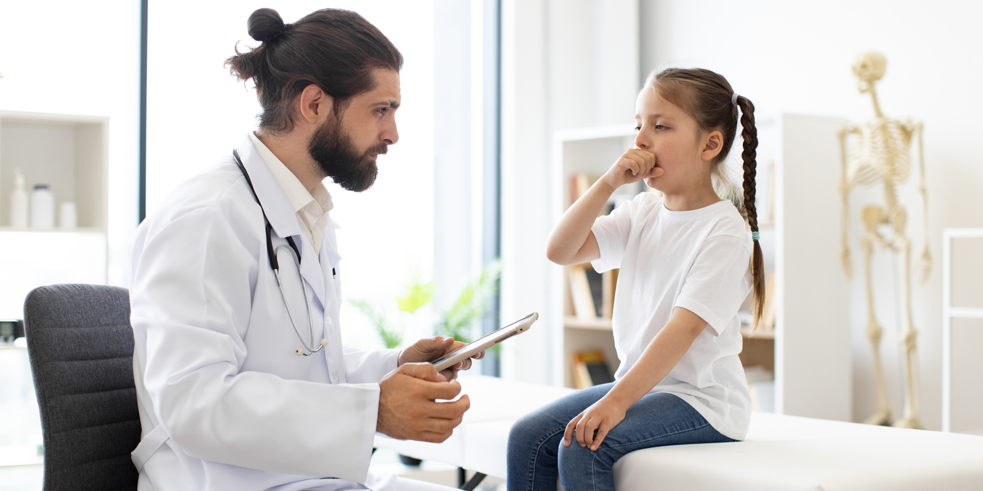 male doctor examines young girl who is coughing