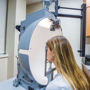 female patient with her head in a machine recieving detailed eye examination 
