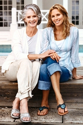 Women sitting on porch senior mother and adult daughter embracing with smiles on a stone bench